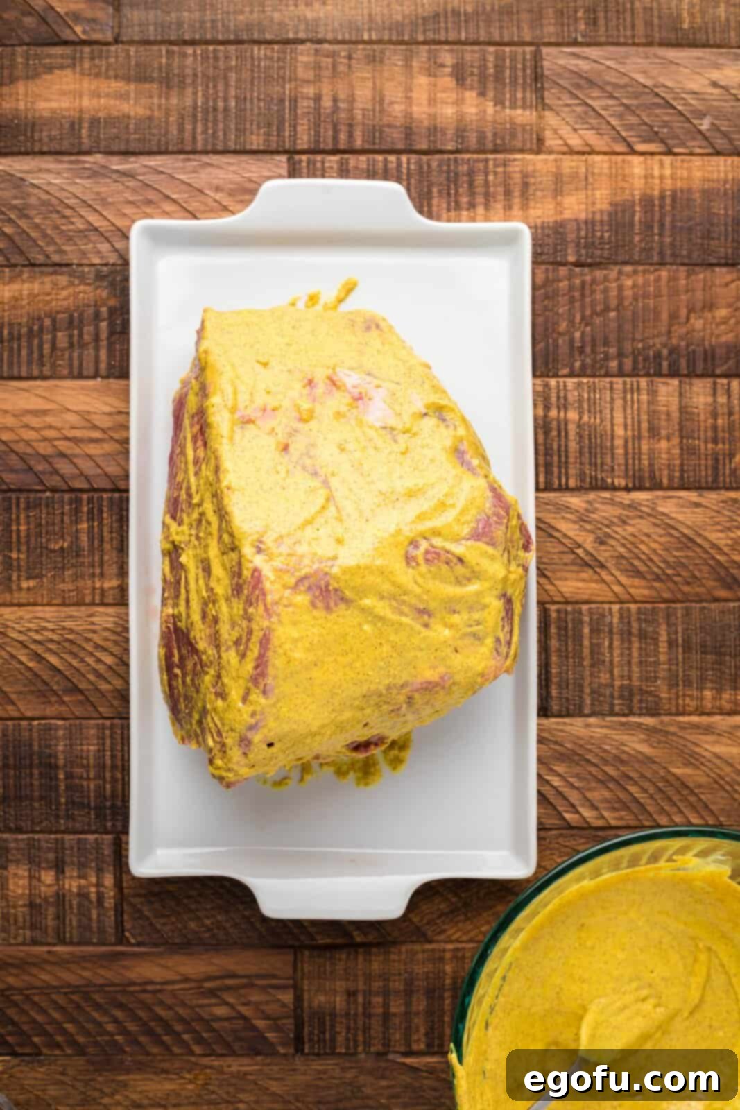 Pitmaster's Smoked Rump 6 A raw rump roast generously coated with the flavorful mustard and garlic paste, ready for the dry rub.