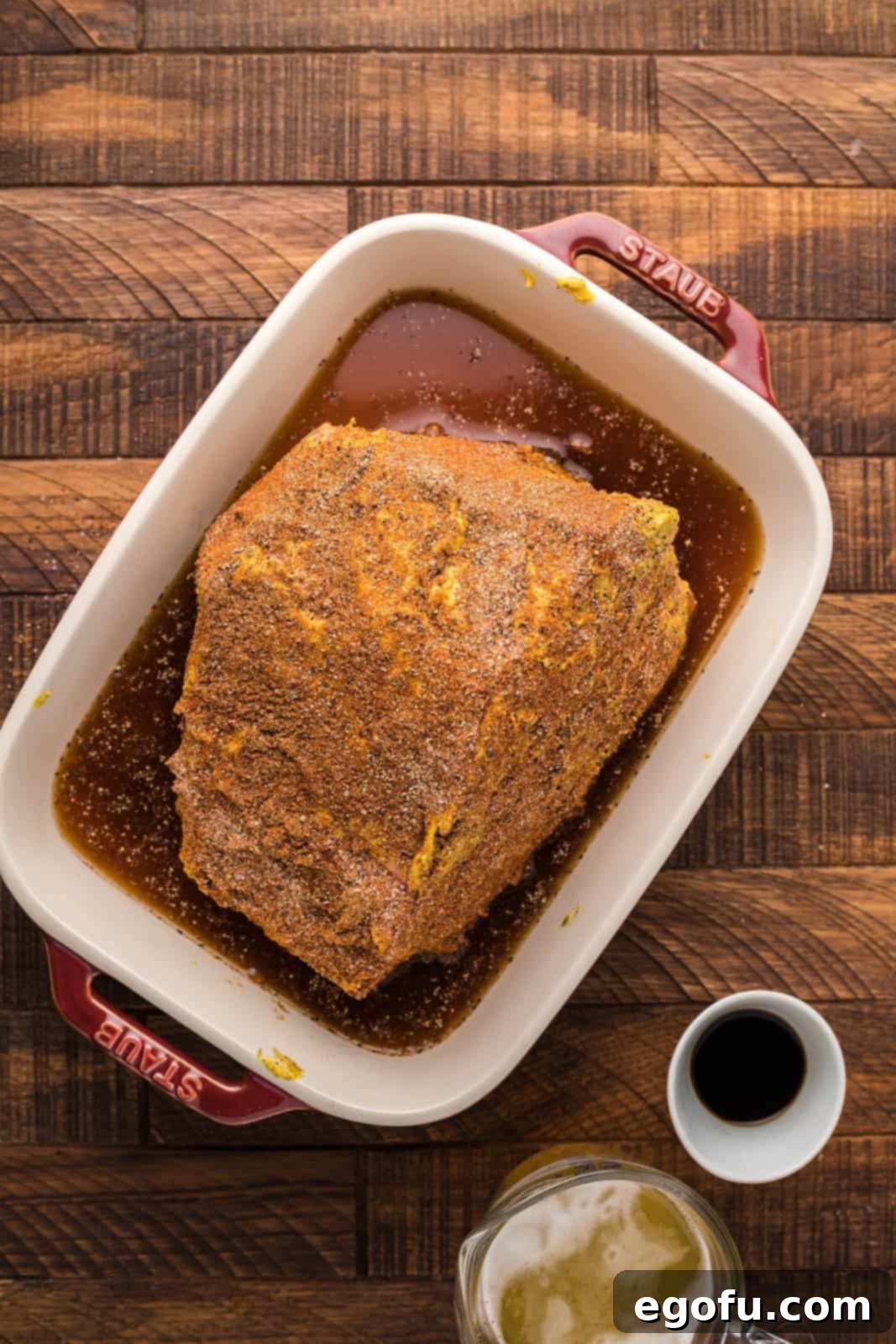 Pitmaster's Smoked Rump 9 A large pan containing the seasoned rump roast, with beef broth and beer poured around its base.