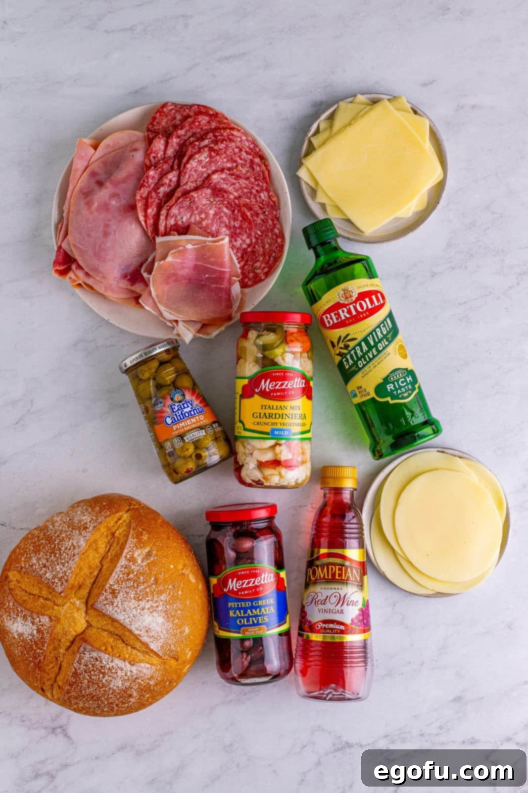 New Orleans' Signature Stack 4 Ingredients needed: giardiniera, green olives with pimento, kalamata olives, olive oil, red wine vinegar, soft white round bread, provolone cheese, deli boiled ham, deli genoa salami, prosciutto and mozzarella cheese.