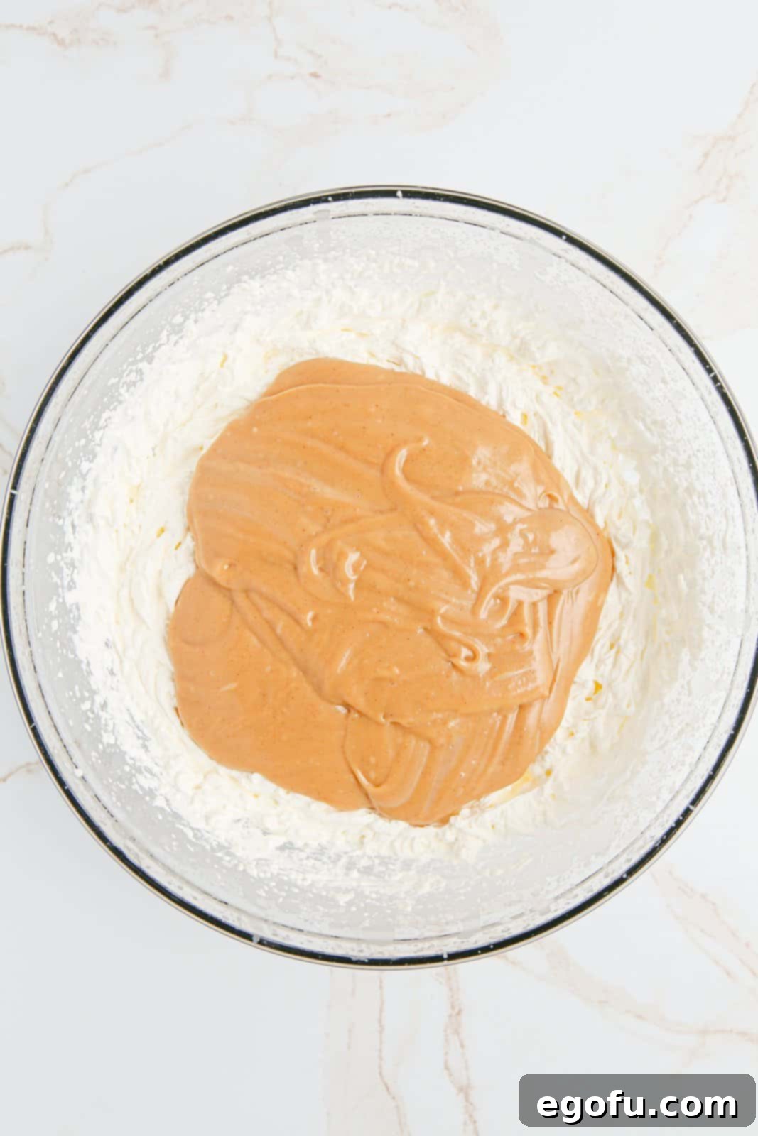 Peanut Butter mixture added to whipped cream in bowl.