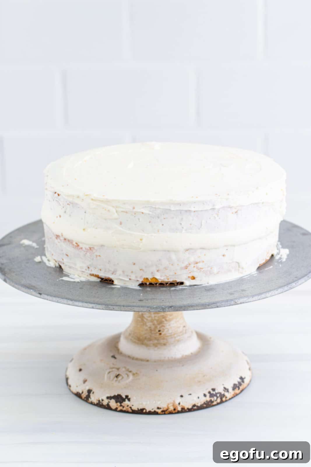 Zesty Lemon Dream Cake 17 Crumb coat frosted over outside of cake on cake stand.