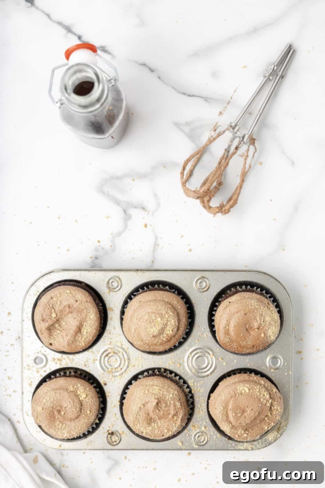Graham cracker crumbs are delicately sprinkled over the soft, fluffy frosting of the cupcakes.