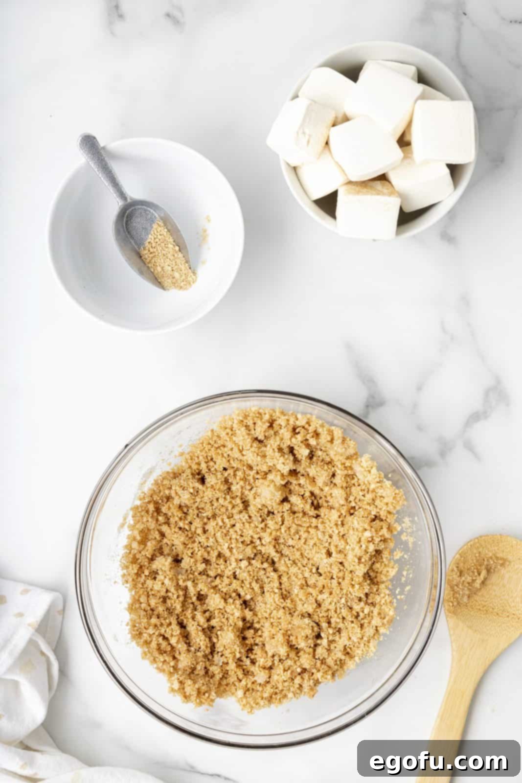 Graham cracker crumbs, sugar, and melted butter are perfectly mixed together in a bowl, ready for the crust.