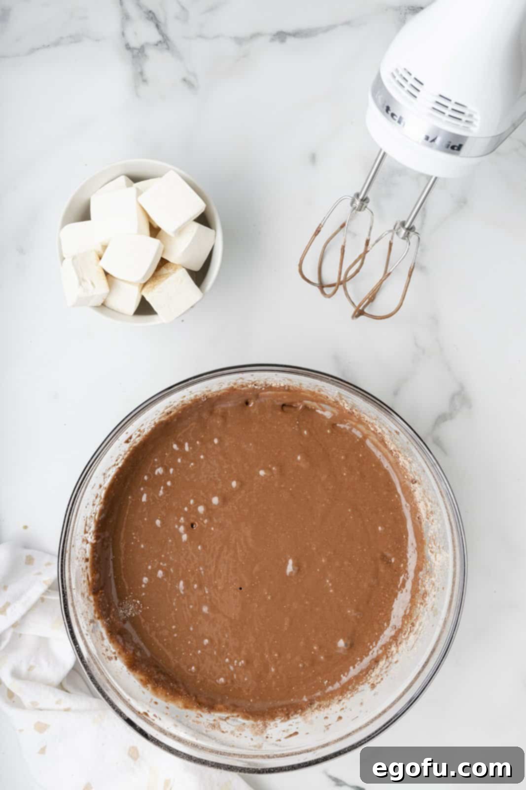 The chocolate cake mix batter is perfectly prepared and smoothed in a mixing bowl, ready to be poured.