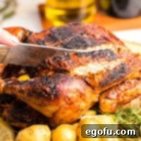 Square image of knife cutting into Air Fryer Whole Roasted Chicken, perfect for a recipe card thumbnail.