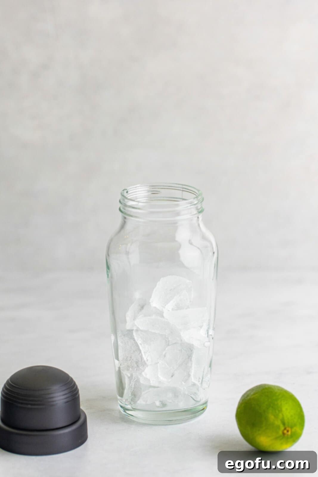 Ice cubes being added to a cocktail shaker, filling it halfway, ready for mixing the Rum Runner ingredients.