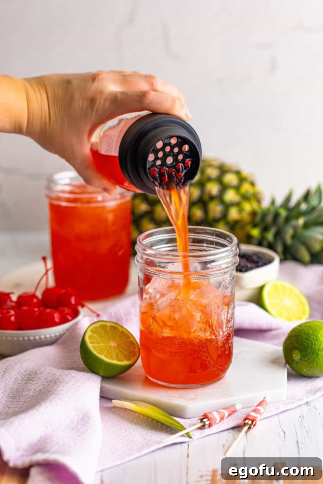 The perfectly mixed Rum Runner Cocktail being poured from the shaker into a glass filled with ice, ready for garnishing.