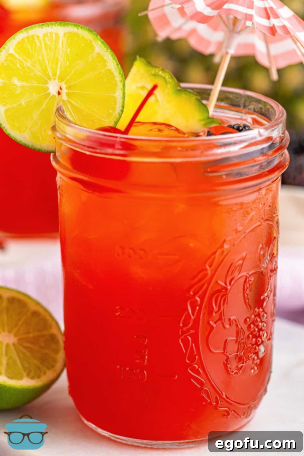 A close-up shot of a garnished Rum Runner Cocktail, highlighting the fresh blackberries, lime, pineapple, and cherry, making it look inviting and delicious.