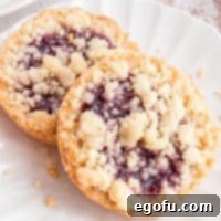 Square image overhead of two Raspberry Tartlets on white plate.