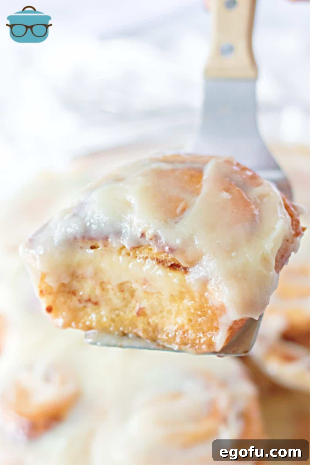 A single gooey Tik Tok Cinnamon Roll being lifted from the pan with a metal spatula, highlighting its soft, pull-apart texture.