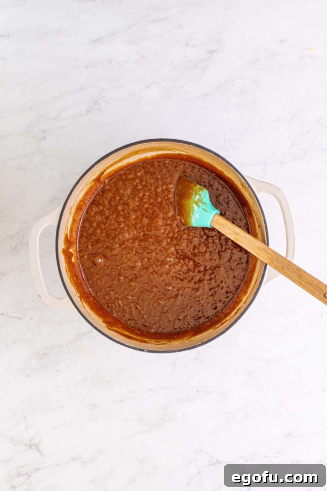 The brownie batter after flour has been gently stirred in, showing a smooth, consistent mixture with no dry patches.