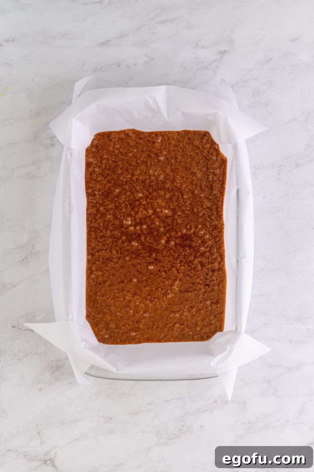 Brownie batter neatly poured into the parchment-lined baking pan, ready for the oven.
