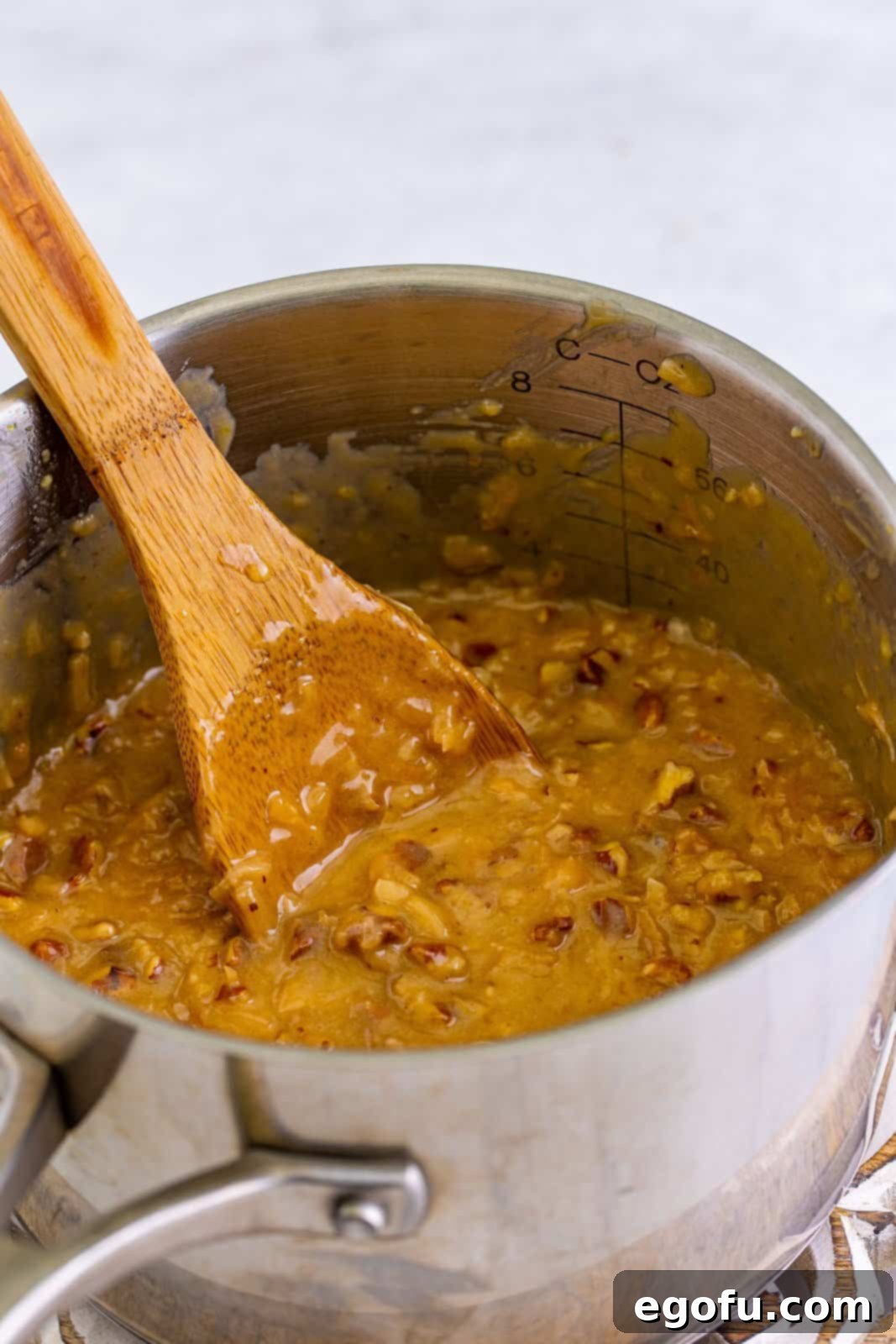 The completed coconut pecan frosting, rich with toasted coconut and chopped pecans, stirred together in the saucepan.