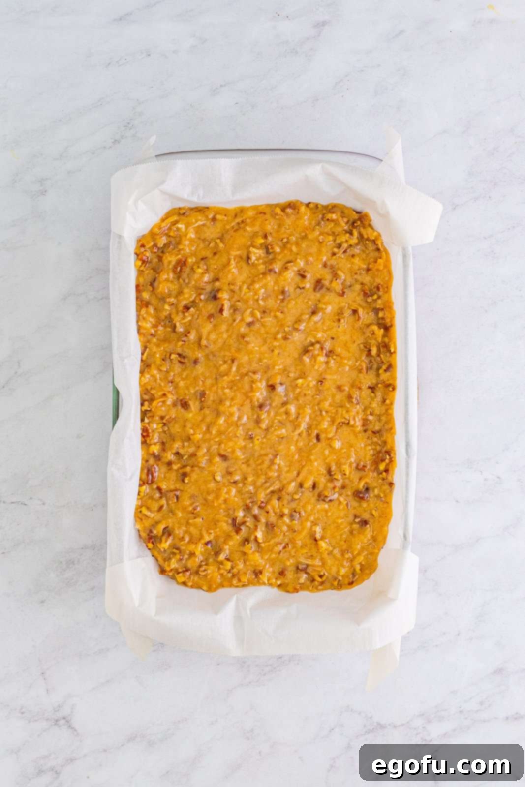 The creamy coconut pecan frosting generously spread over the cooled German Chocolate Brownies in the baking pan.