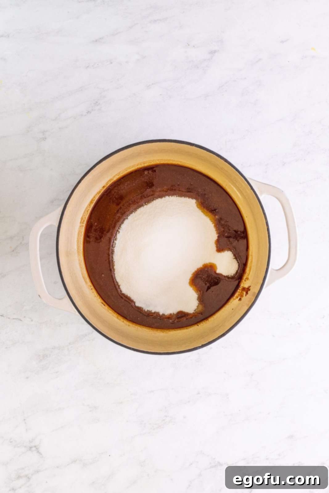 Granulated sugar freshly added to the melted chocolate and butter mixture, being prepared for whisking.