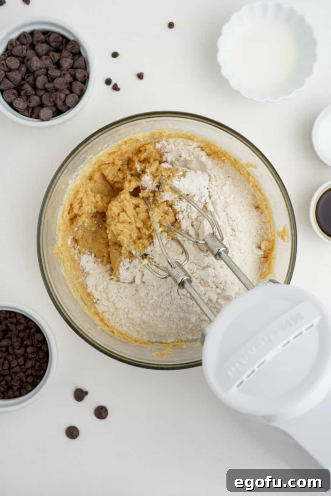 Choc-Chip Dough Delight 6 Dry ingredients, including heat-treated flour and salt, being added to the creamy butter and sugar mixture in a bowl.