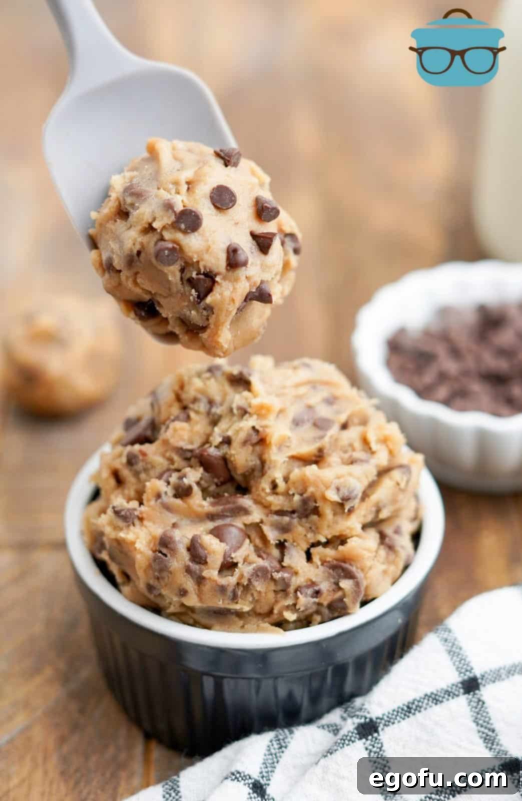 Choc-Chip Dough Delight 10 A spoon lifting a perfect scoop of Edible Chocolate Chip Cookie Dough out of a ramekin, showcasing its texture and chocolate chips.
