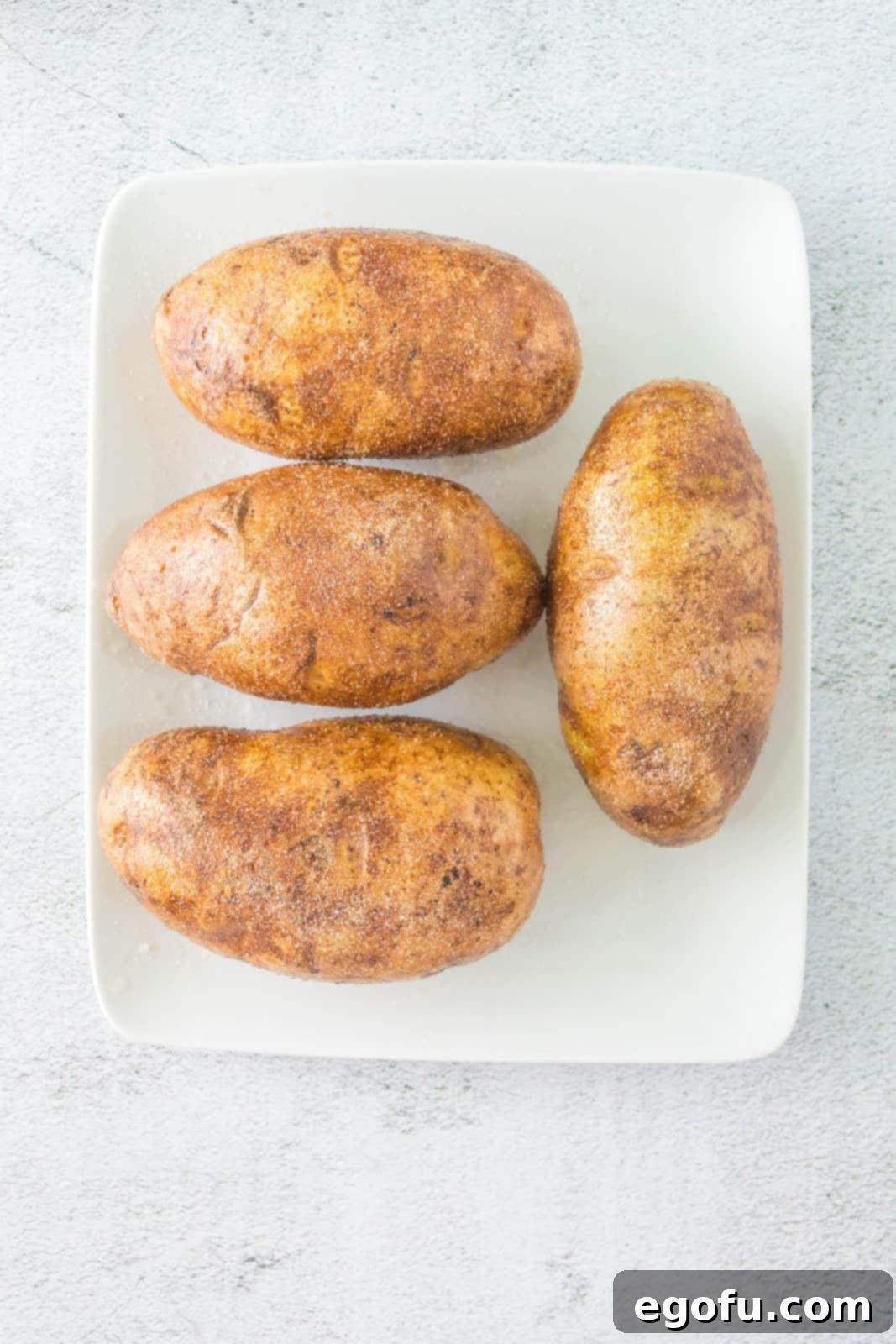 Potatoes individually poked with a fork, then thoroughly rubbed with olive oil and seasoned with salt and onion powder.