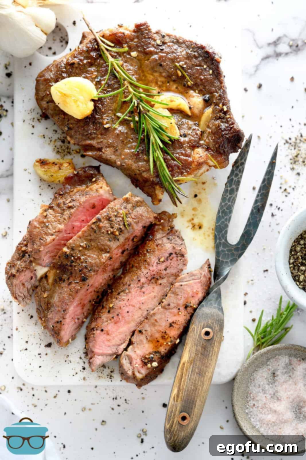 Overhead of Pan Seared Steak cut up on white plate with whole steak next to it, showcasing a perfect medium-rare.