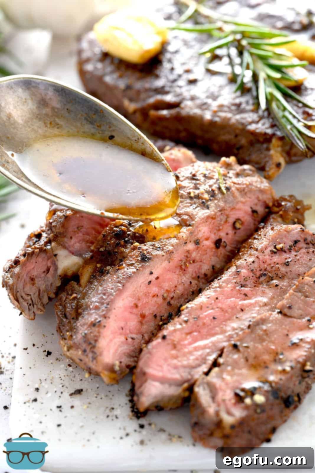Sliced Pan Seared Steak on a cutting board with a spoon drizzling pan drippings over it, highlighting its juicy interior.