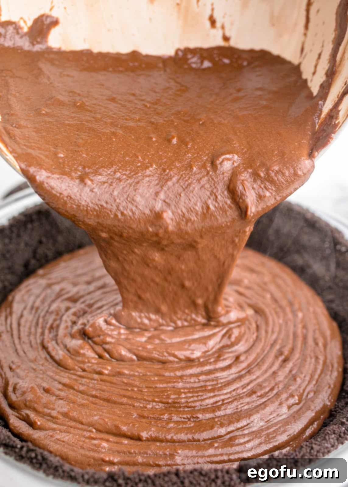Warm chocolate filling being poured into the chilled Oreo crust.