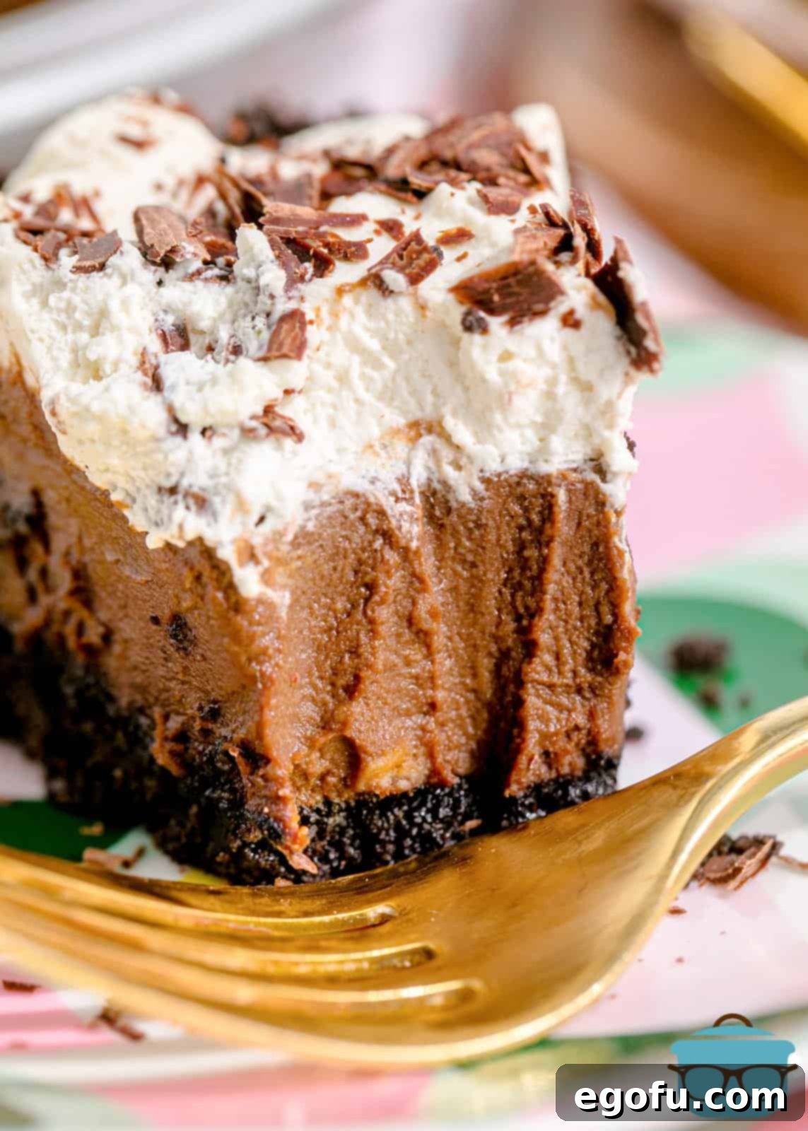 Close-up of a slice of Chocolate Cream Pie with a bite taken out, highlighting the creamy filling, crunchy crust, and whipped topping.