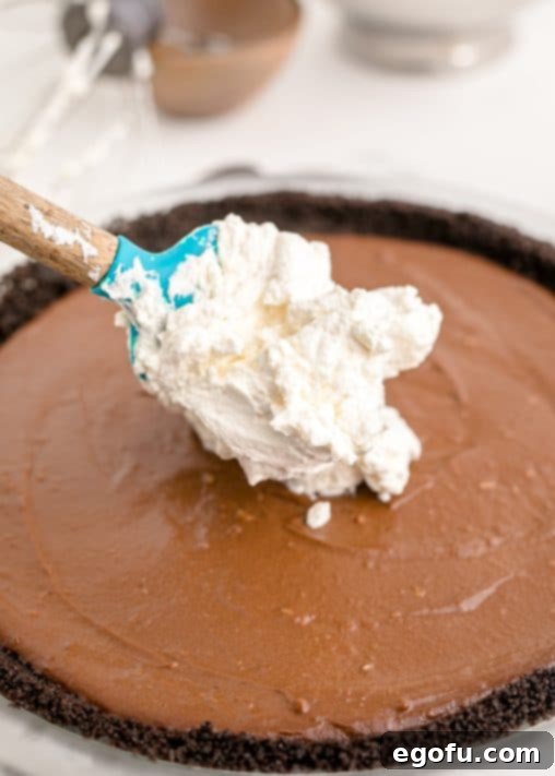 Whipped cream being added to top of pie filling.