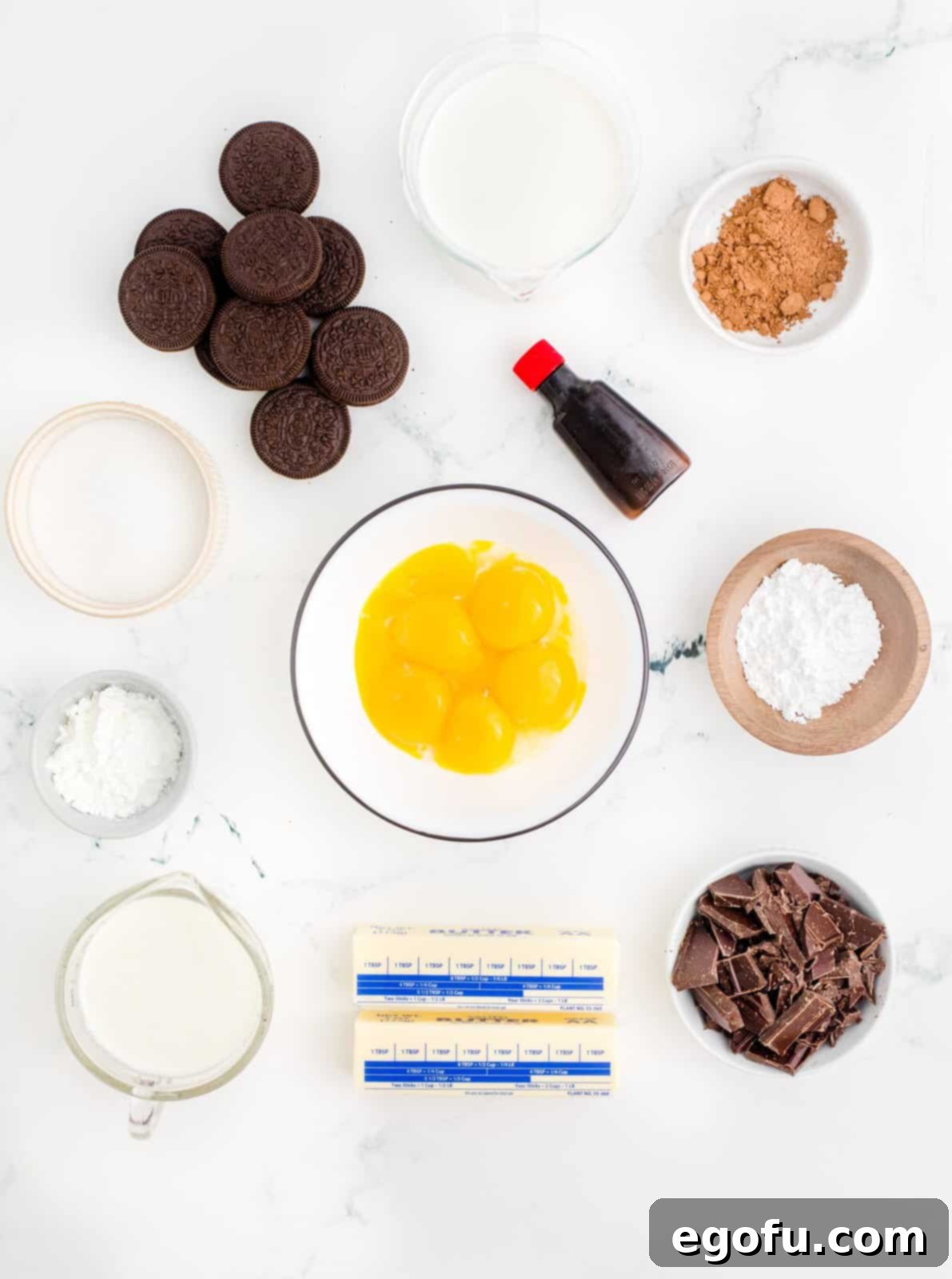 A flat lay image displaying all the ingredients needed for Chocolate Cream Pie: Oreo cookies, salted butter, granulated sugar, cornstarch, cocoa powder, half and half, egg yolks, semi-sweet chocolate bar, vanilla extract, heavy cream, and powdered sugar.