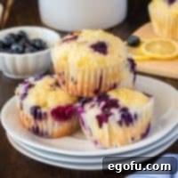 Square image close up of stacked Lemon Blueberry Muffins on white plate.