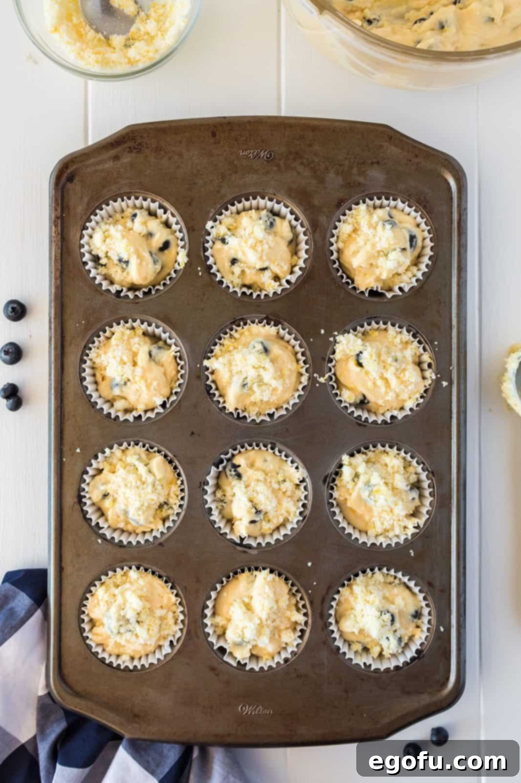 Lemon sugar mixture sprinkled on top of muffin batter in tin.
