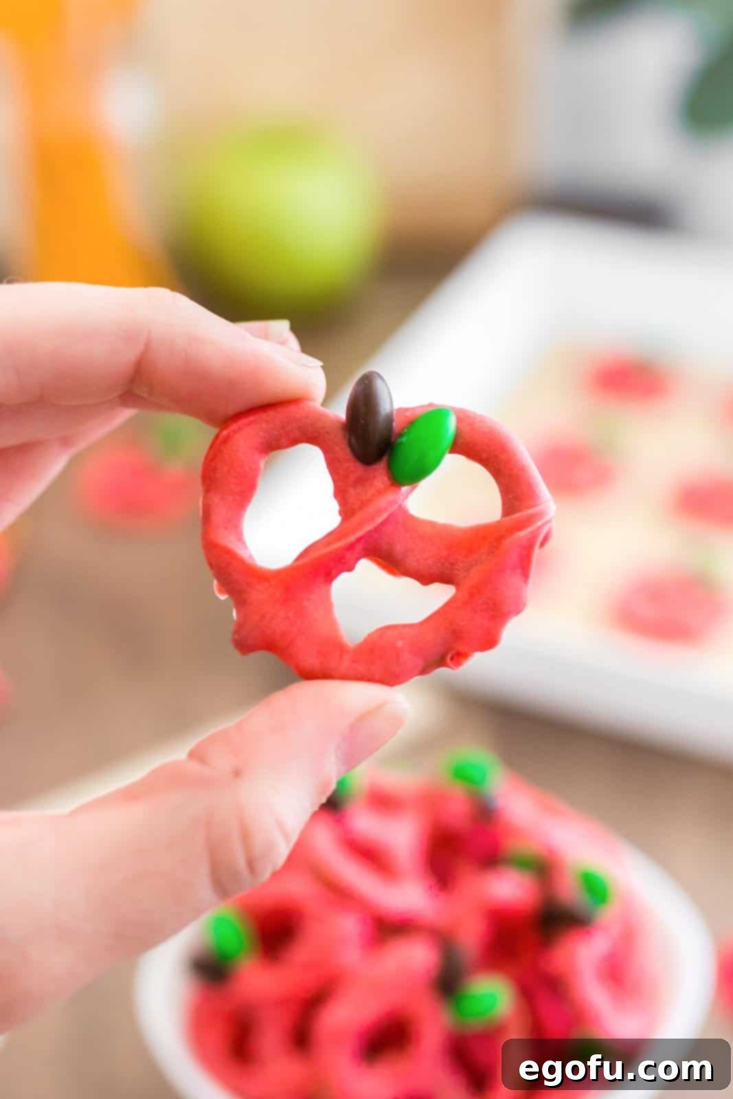 Hand holding up one pretzel that is made to look like an apple.