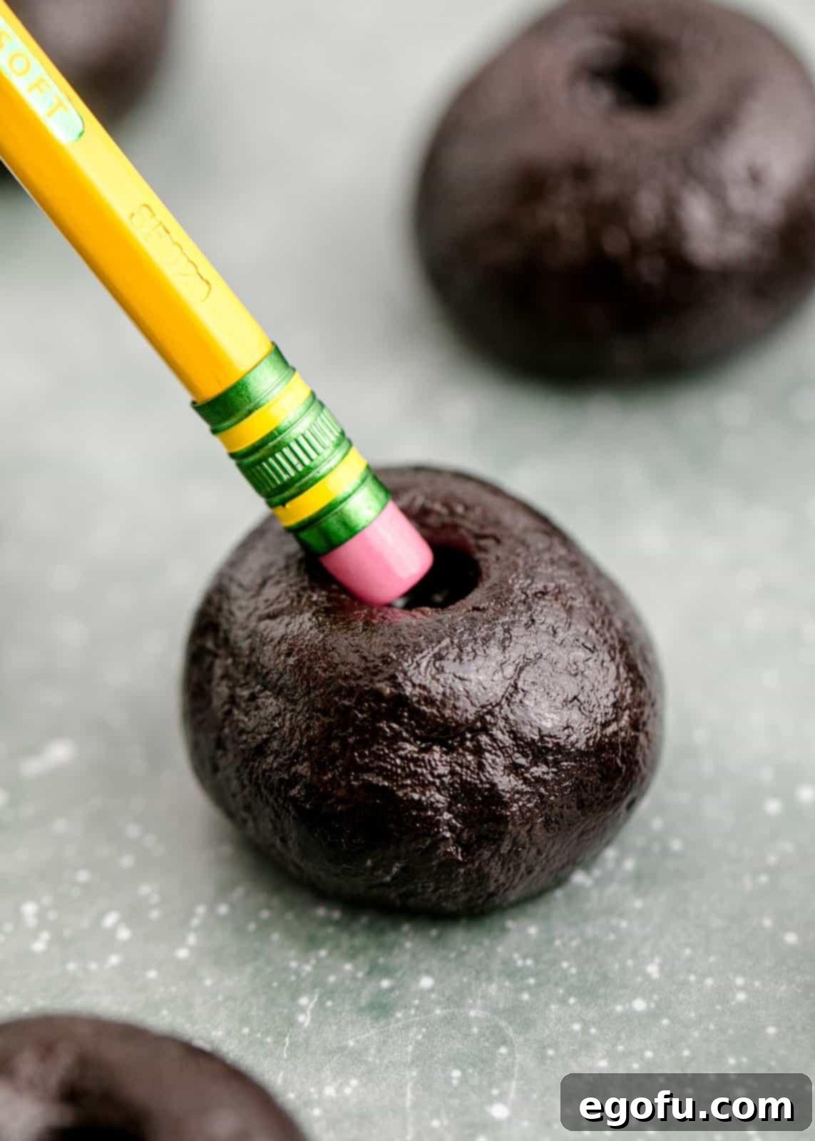 Oreo truffles shaped into uniform balls with an indent being made in the top to resemble an apple, a key step in their transformation.