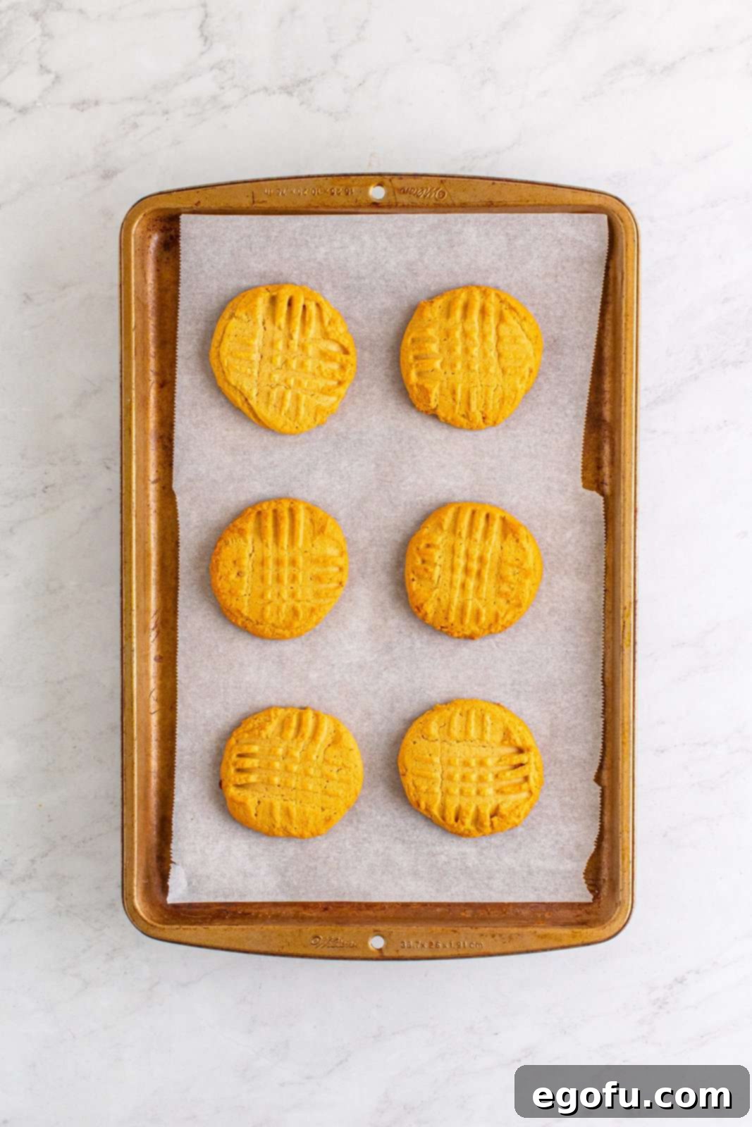 Freshly baked cookies cooling on a baking pan after being removed from the oven.