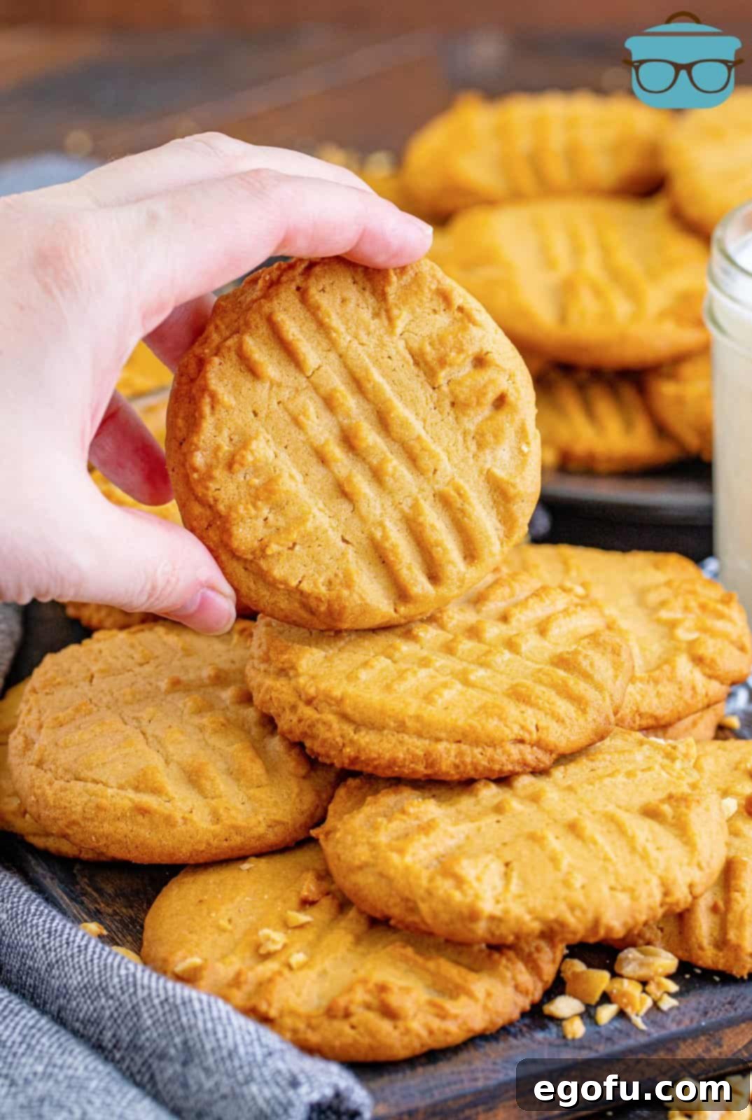 Stacked Lunch Lady Peanut Butter Cookies with a hand holding one up slightly, ready to be enjoyed.