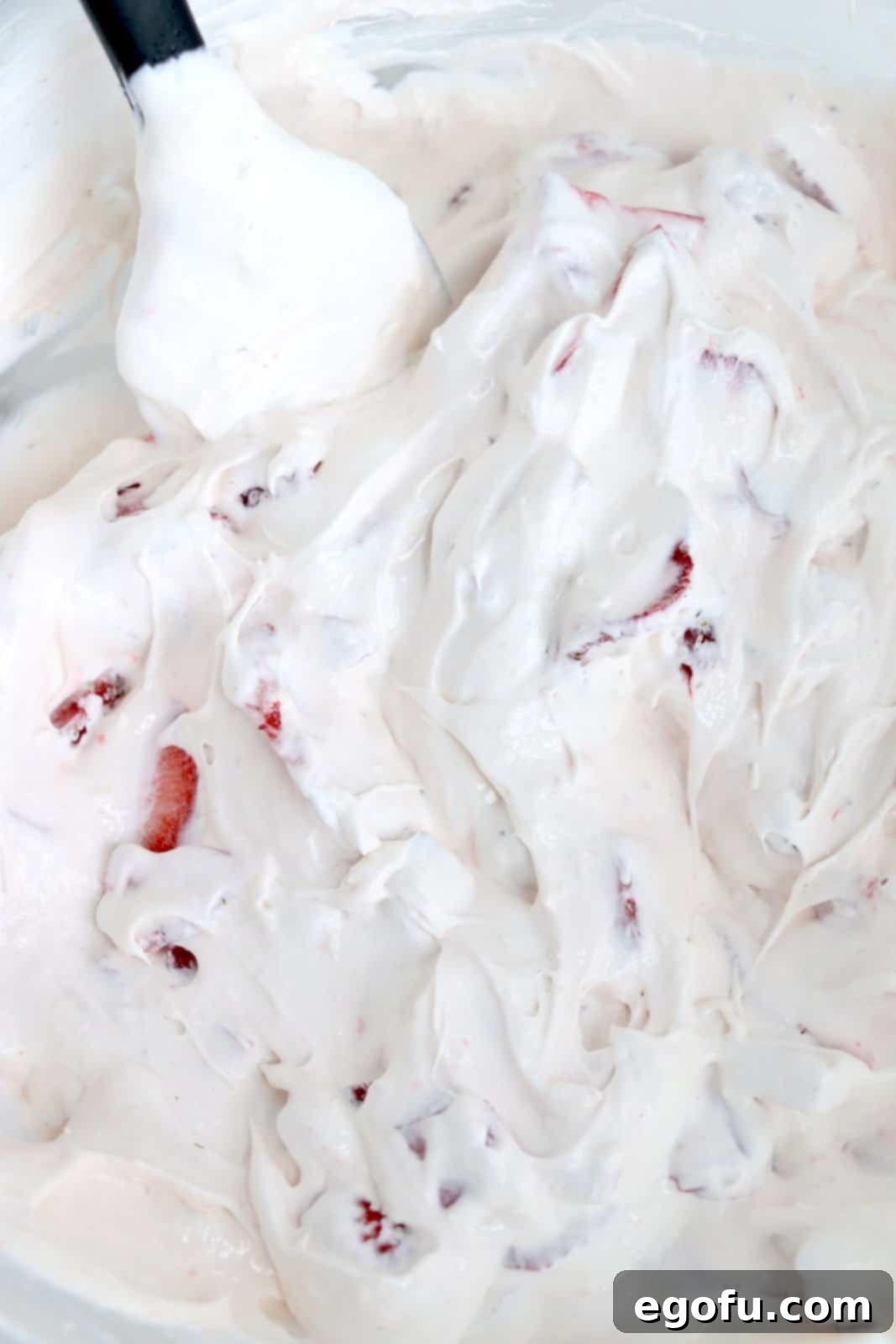 The fully combined Strawberry Cheesecake Fluff mixture in a bowl, with strawberries evenly folded into the creamy, fluffy base.