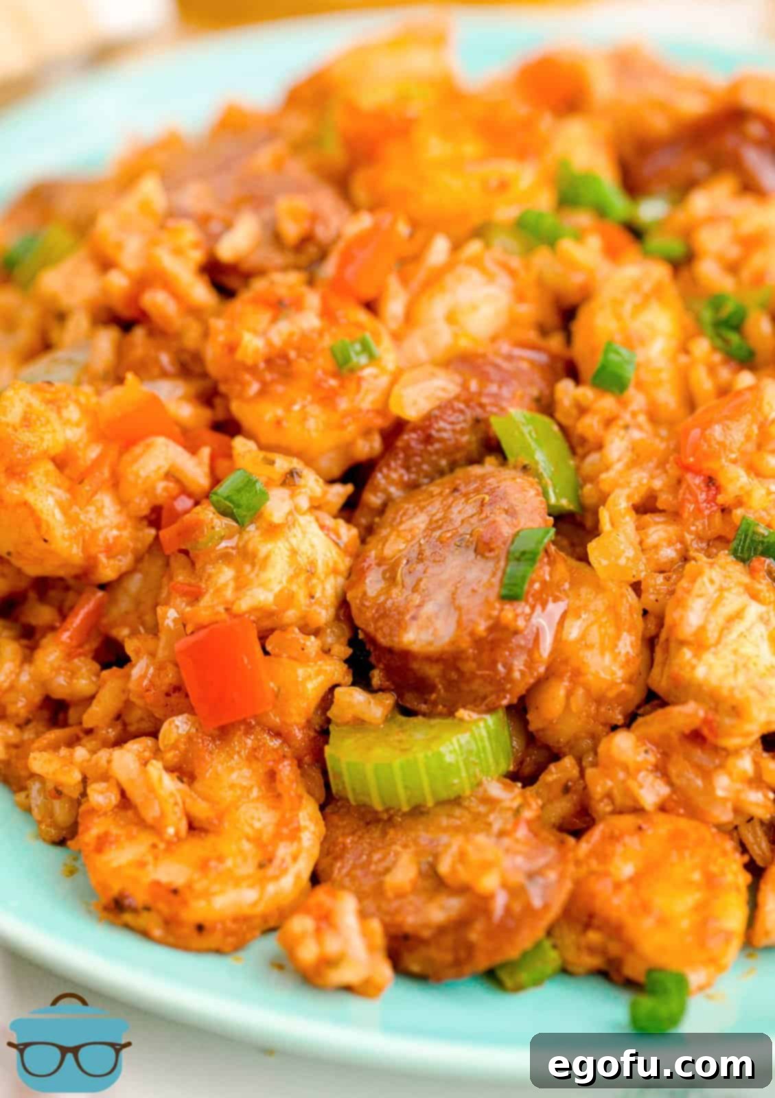 Close up of authentic Louisiana Jambalaya on a blue plate, showcasing the rich colors and textures of chicken, sausage, shrimp, and rice.