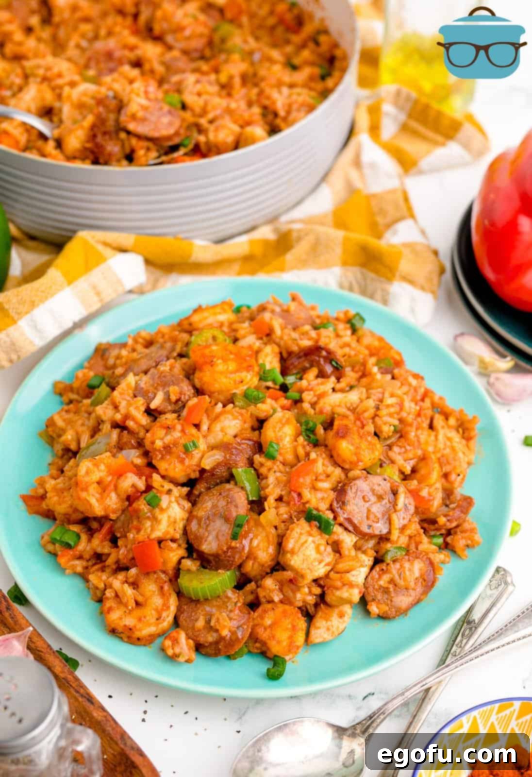 Slightly overhead photo of a serving of Louisiana Jambalaya on a blue plate with the cooking pot blurred in the background, showing off the hearty texture.