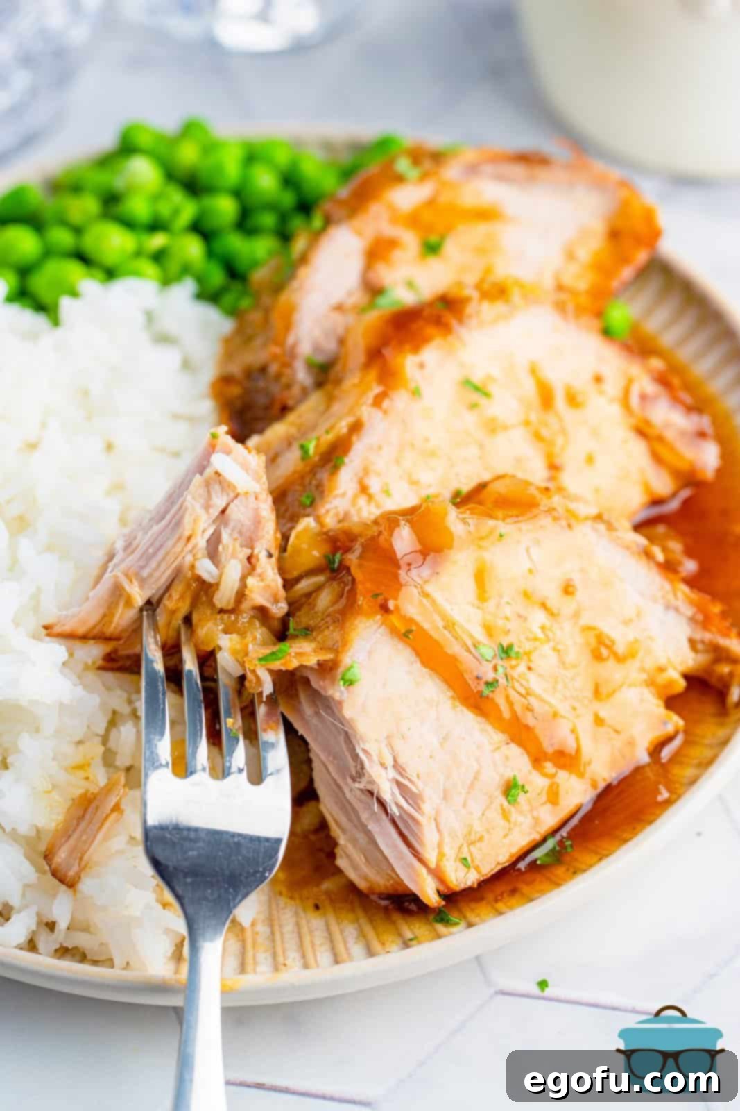 Effortless Crock Pot Pork Loin 2 Crock Pot Pork Loin on plate with sides with fork holding a bite from the pork.