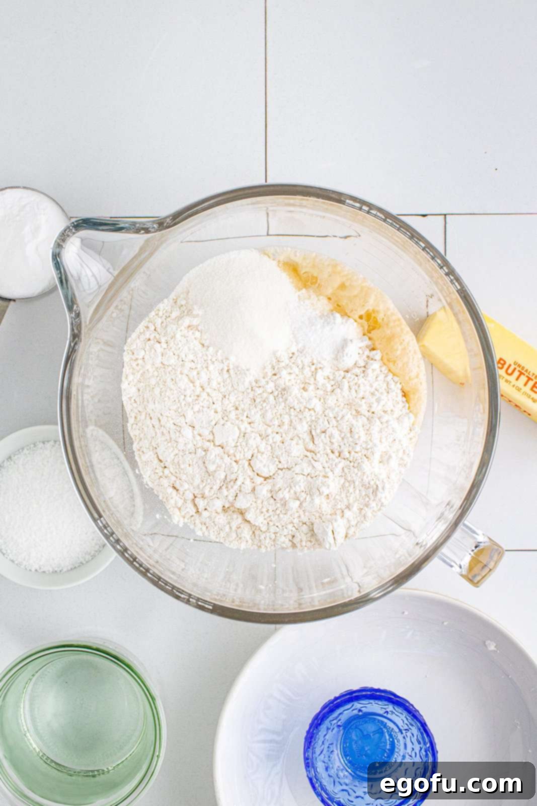 Flour, sugar, and salt added on top of the foamy yeast mixture in the stand mixer bowl.