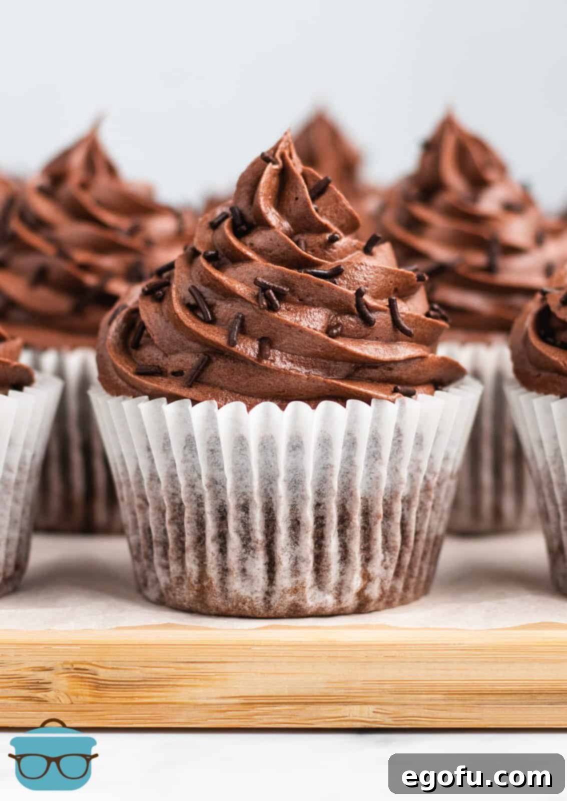 Easy Chocolate Cupcakes topped with sprinkles on wooden platter.