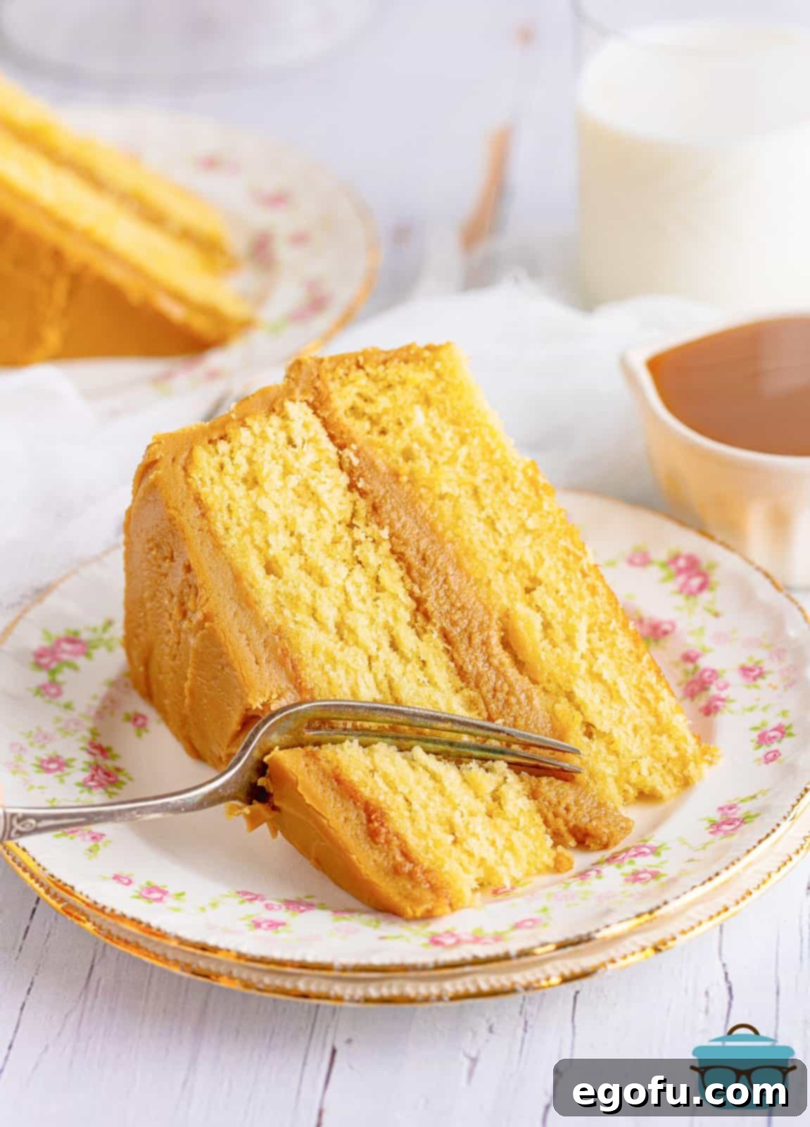 Golden Southern Caramel Delight 2 Slice of Southern Caramel Cake on white plate with fork cutting a bite out.