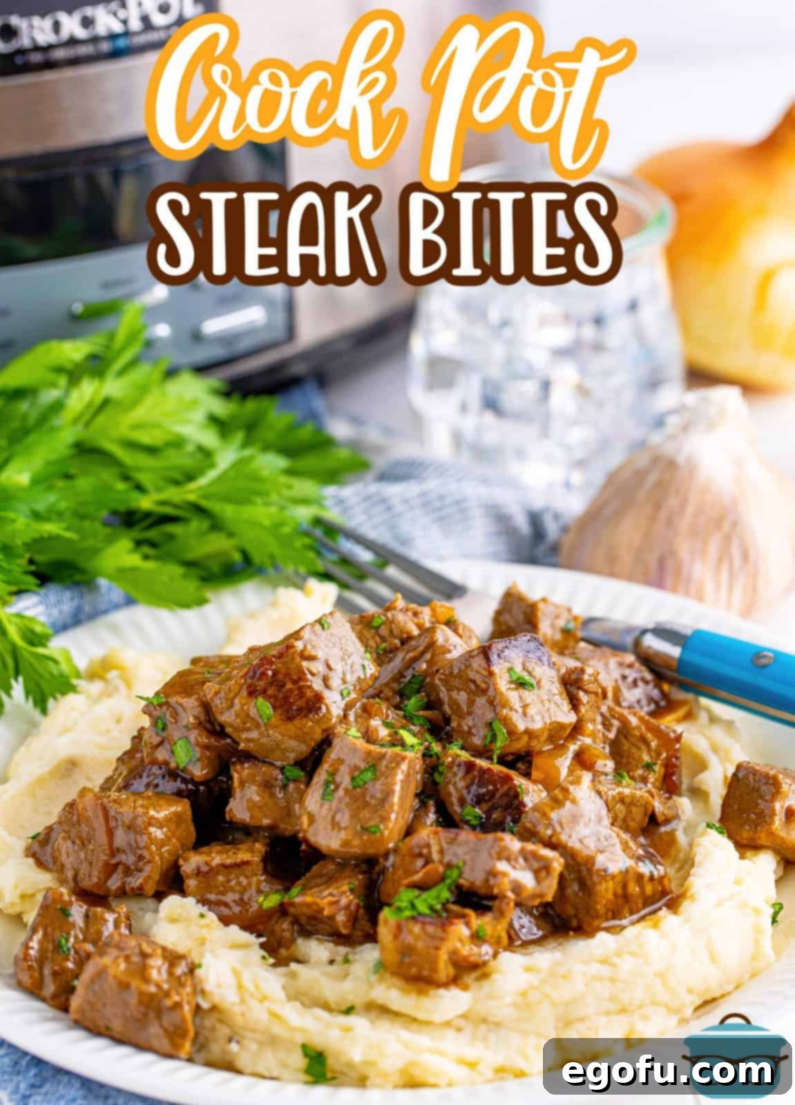 Pinterest image of Slow Cooker Garlic Butter Steak Bites with mashed potatoes, a slow cooker in the background, and fresh parsley garnish.