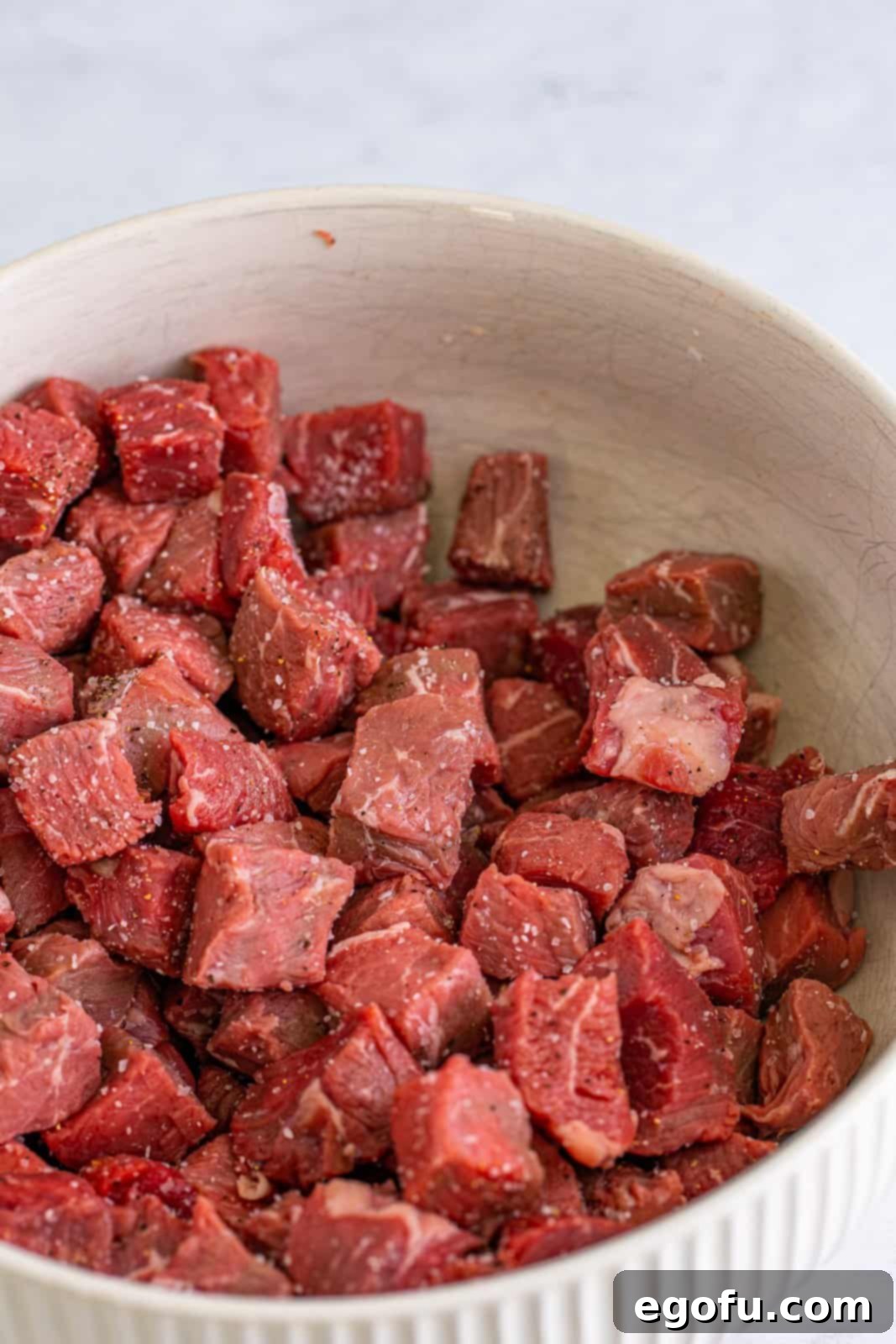 Steak mixed together with salt and pepper in a bowl, ready for searing.