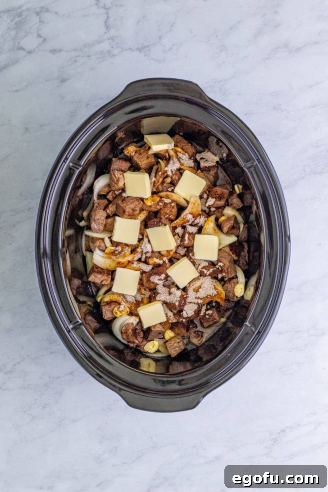 Beef stock, au jus mix, and butter added to slow cooker, showcasing layers of flavor.