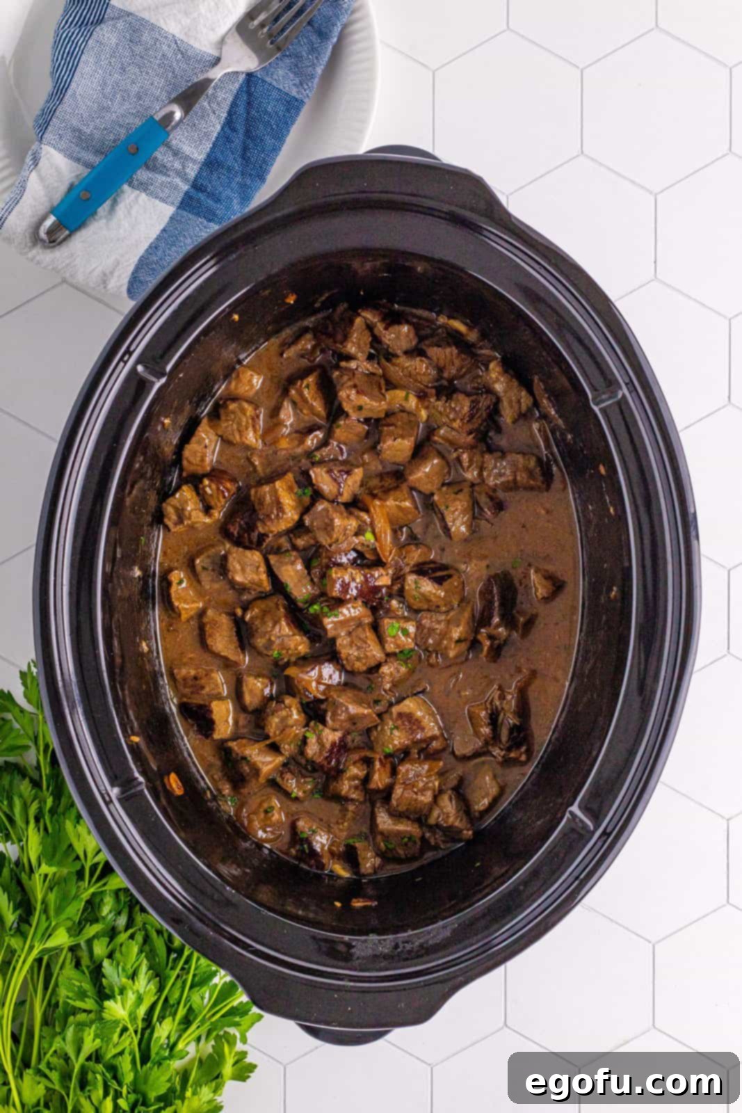 Finished garlic butter steak bites in the slow cooker, rich with gravy and tender meat.