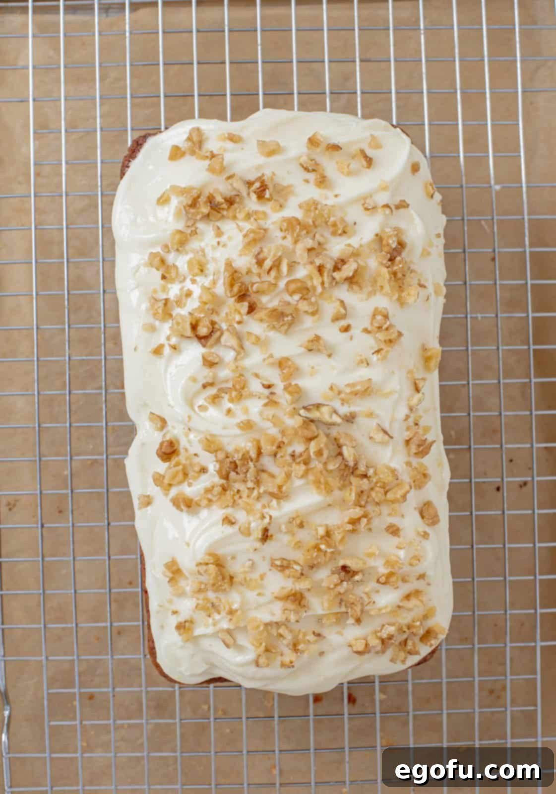 Frosting spread on cooled cake and topped with chopped walnuts.