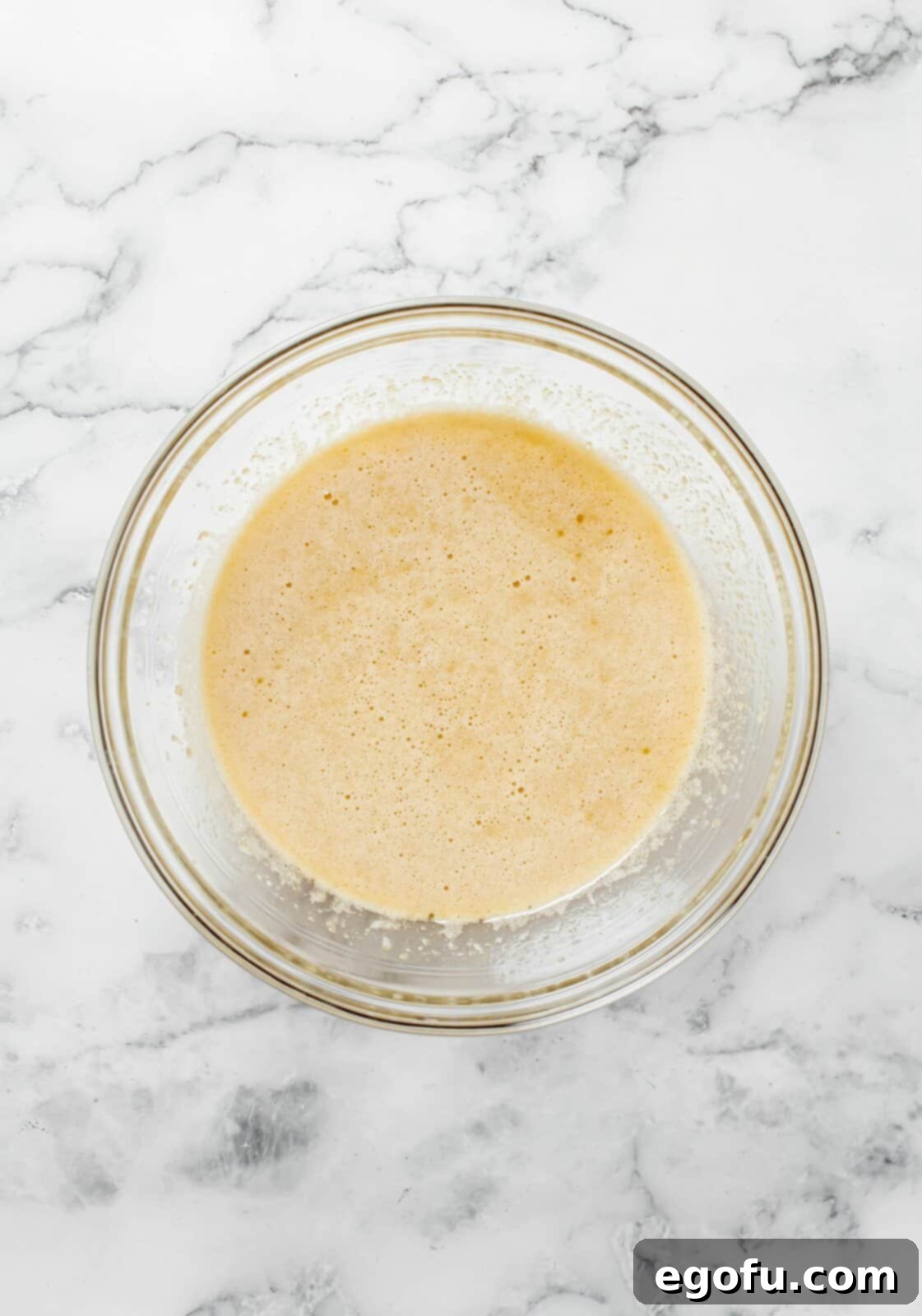 Eggs, butter, sugars and vanilla mixed together in bowl.