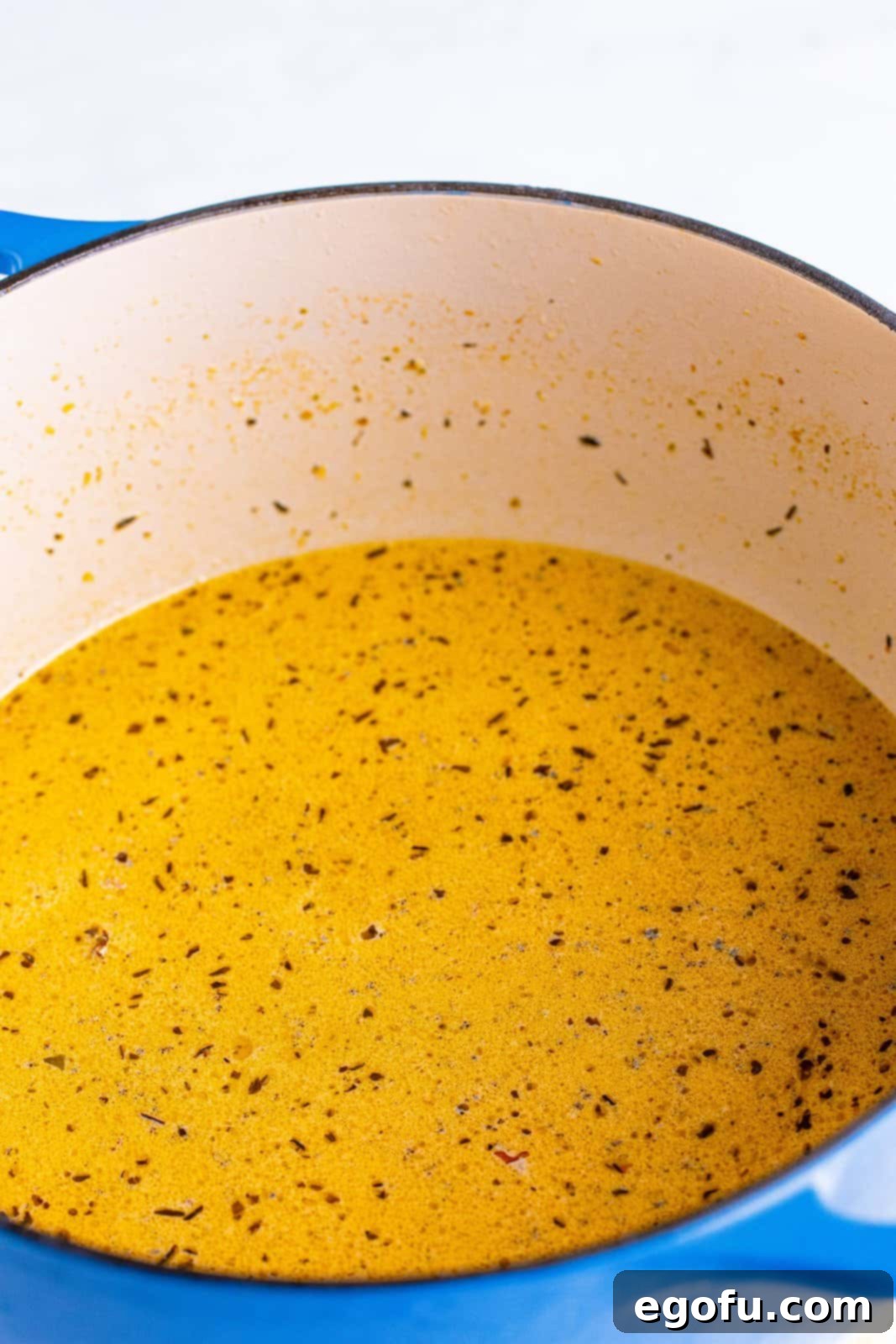 Chicken stock and heavy cream added to dutch oven with ingredients and stirred, creating the sauce base.