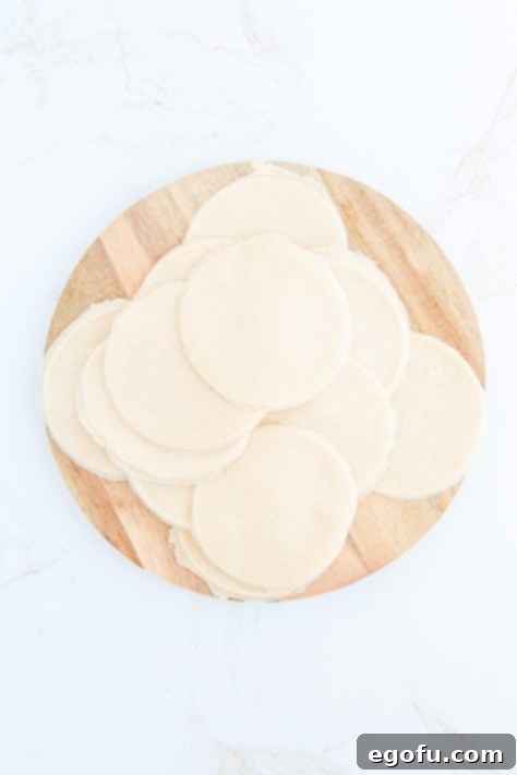 Pie crust cut into circles on wooden board.