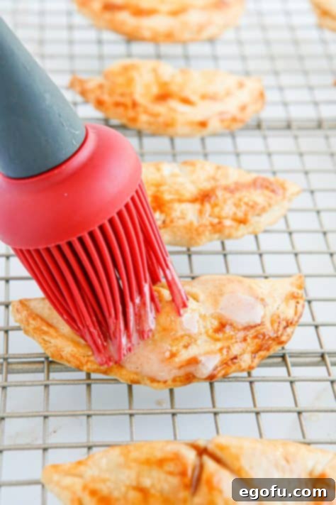 Pastry brush brushing hand pies with glaze.